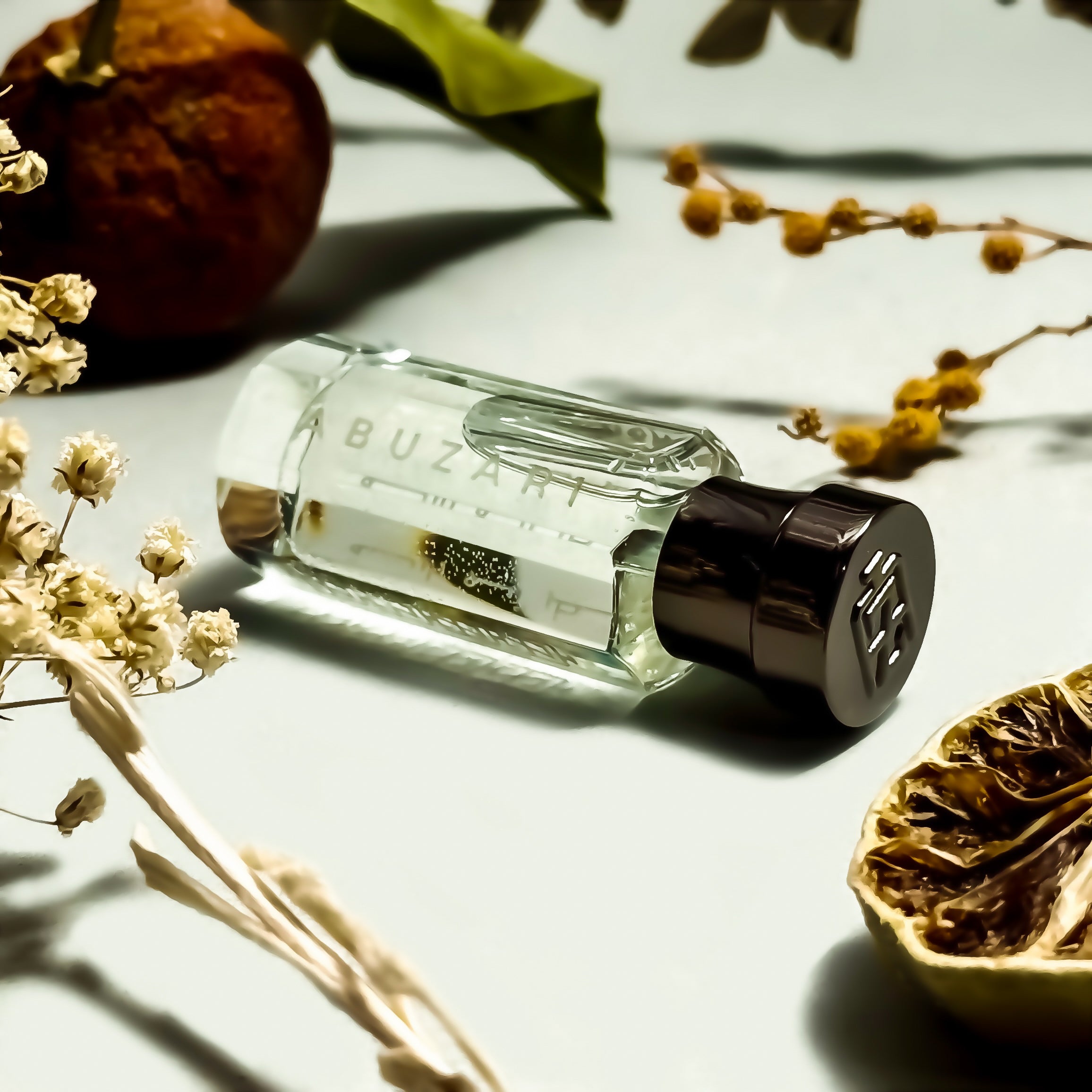 Abu Zari perfume bottle on a light surface with dried flowers and leaves