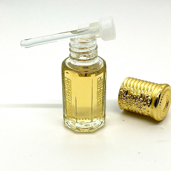 Oud Wood Arabian perfume oil inside attar bottle with Abu Zari brand logo, glass stick applicator on top of bottle with gold royal crown cap.