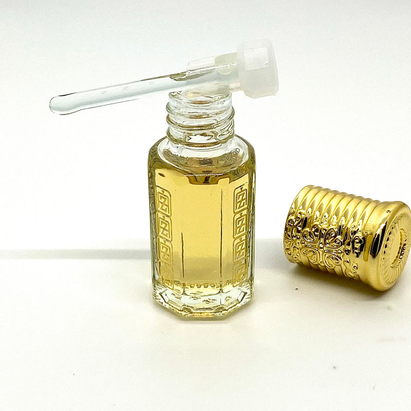 Oud Wood Arabian perfume oil inside attar bottle with Abu Zari brand logo, glass stick applicator on top of bottle with gold royal crown cap.